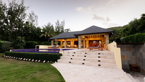 A house with a swimming pool, outdoor seating, and a staircase leading to the entrance.