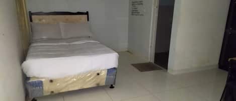 Una habitación pequeña y limpia con una cama individual, una puerta y una pared con una cita motivacional.