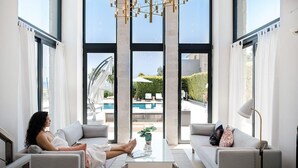 Una sala de estar moderna con un ventanal grande, vistas a la piscina y un diseño minimalista.