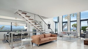 Una sala de estar moderna con una escalera, un sofá, una mesa de centro y un comedor.