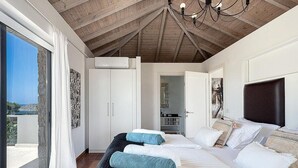 Un dormitorio con una cama grande, ventilador de techo y vistas al exterior.