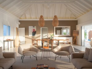 Relax in this spacious living room with a dining area, large mirror, and natural light pouring in through the windows.