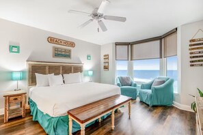 Ein Schlafzimmer mit einem großen Bett, einem Deckenventilator, Meerblick und einem Schild mit der Aufschrift 'BEACH HOUSE'.