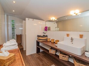 Sink, mirror, and vanity in a clean, minimalist bathroom with a wooden floor.