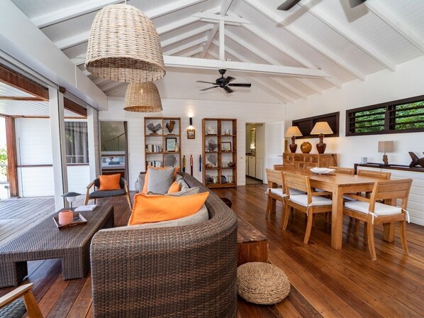 Relax in a spacious interior with a high ceiling, featuring a wicker sofa and dining table.