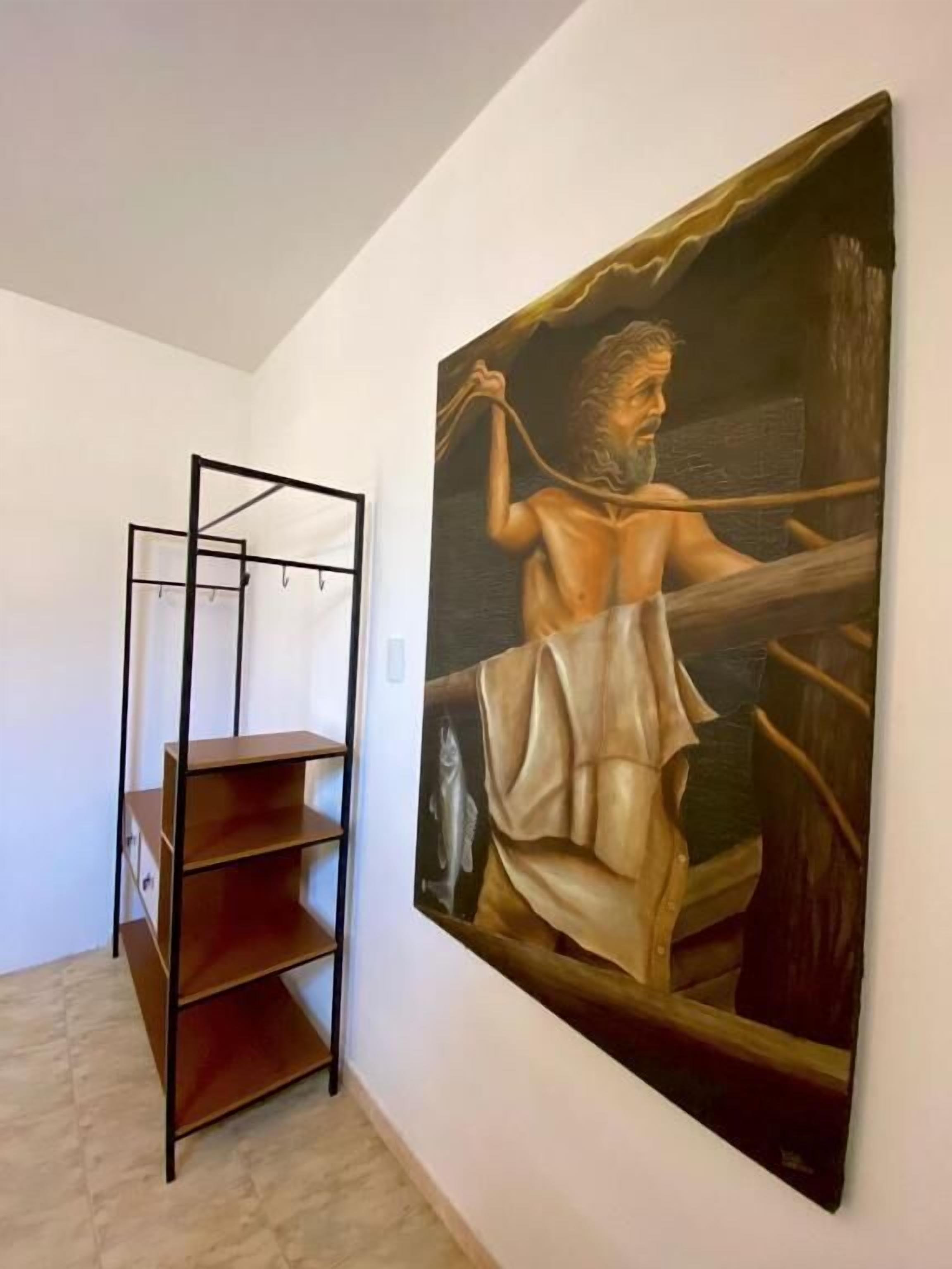 Una habitación con una estantería metálica y un cuadro grande en la pared.