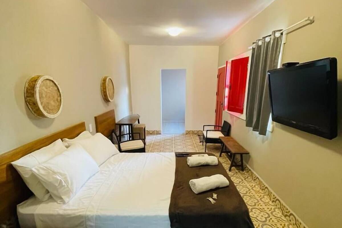 Une chambre d’hôtel avec un lit, un bureau, une chaise, une télévision et un sol à motifs.