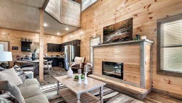 Un vaste espace de vie doté d’une cheminée, de murs en bois et d’un coin repas.