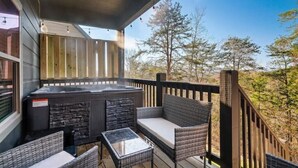 Un espace extérieur aménagé, abrité et doté d’un jacuzzi, de meubles en osier et offrant une vue sur les arbres.