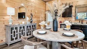 Un intérieur en bois avec une table de salle à manger ronde, des chaises, un buffet et un miroir.