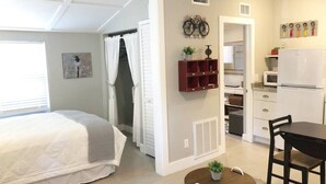 A compact, well-lit room with a bed, a small dining table, and a kitchenette. - Cozy Apartment Overlooking Downtown Dunedin (Dunedin)