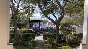 A pathway leading to a gazebo with a covered seating area, surrounded by greenery and a white fence. - Cozy Apartment Overlooking Downtown Dunedin (Dunedin)