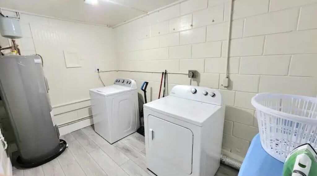 Un cuarto de lavandería con dos lavadoras, un secador y una cesta de ropa.