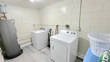 Un cuarto de lavandería con dos lavadoras, un secador y una cesta de ropa.