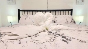 A bed with a white and black patterned bedspread, two bedside lamps, and a black headboard.