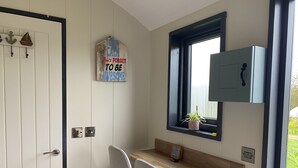 Eine kleine Küche mit Holzarbeitsplatte, einem Stuhl, einem Fenster mit Aussicht und einem an der Wand befestigten Schrank.
