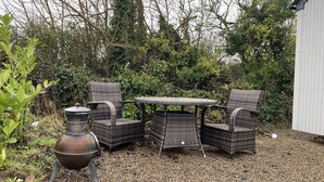 Eine Terrasse mit Korbmöbeln und einem Metalltopf.