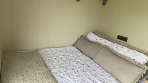 Ein Schlafzimmer mit einem Bett, Kissen, einem Regal mit Büchern und einer Steckdose.