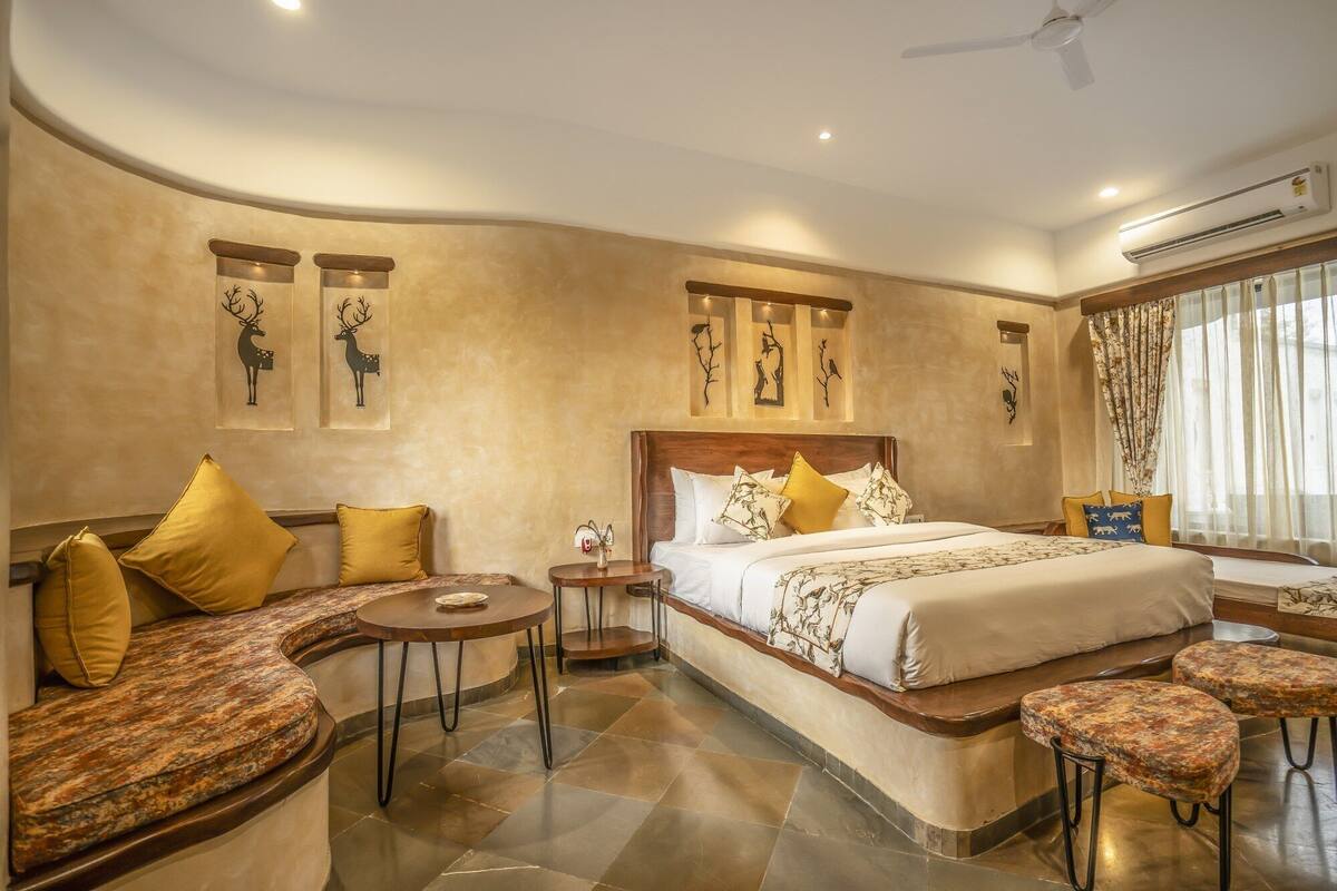 A spacious bedroom with a large bed, a seating area with a table, and artwork on the walls.