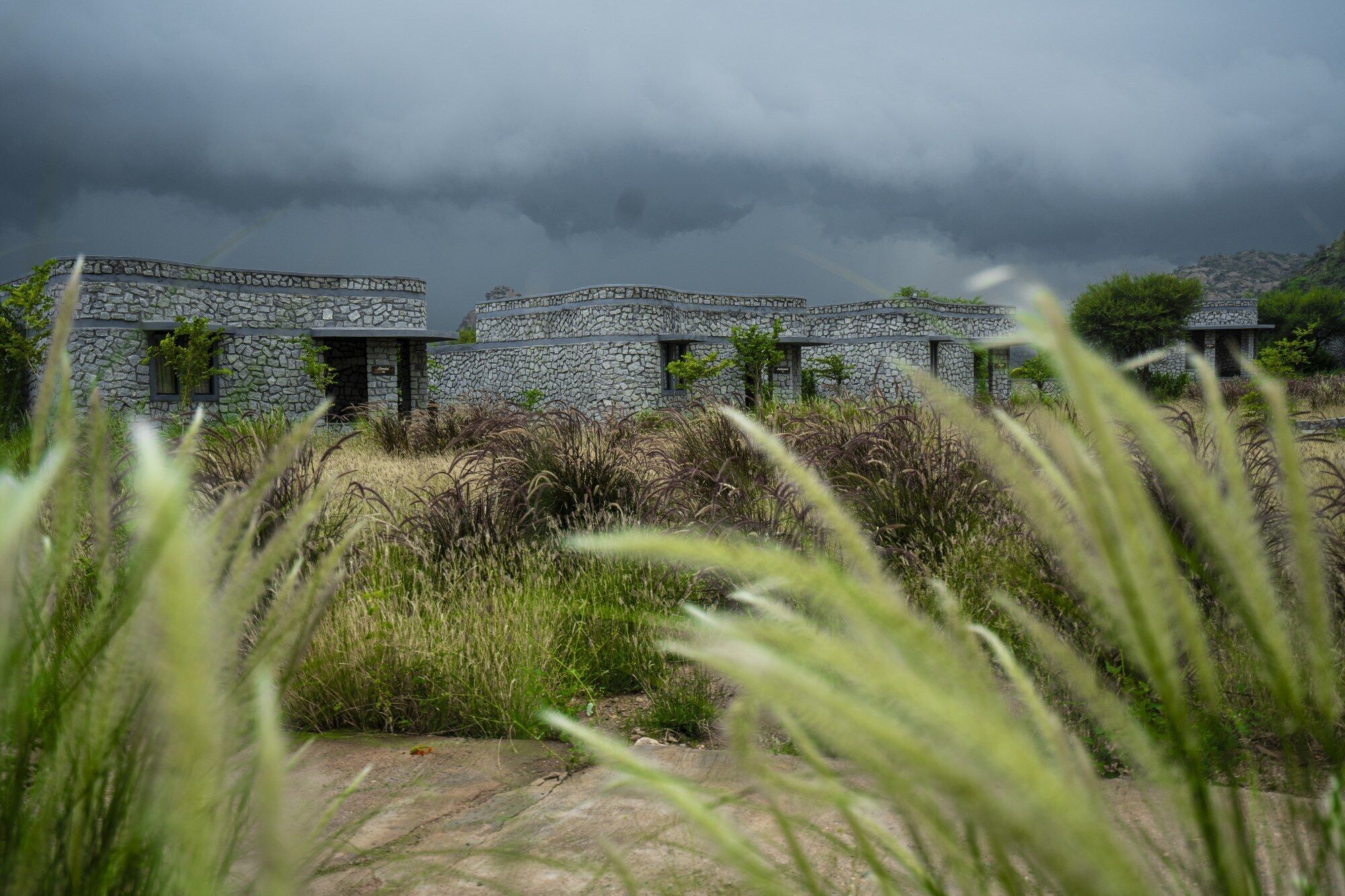 A stone building with multiple rooms, surrounded by natural vegetation.