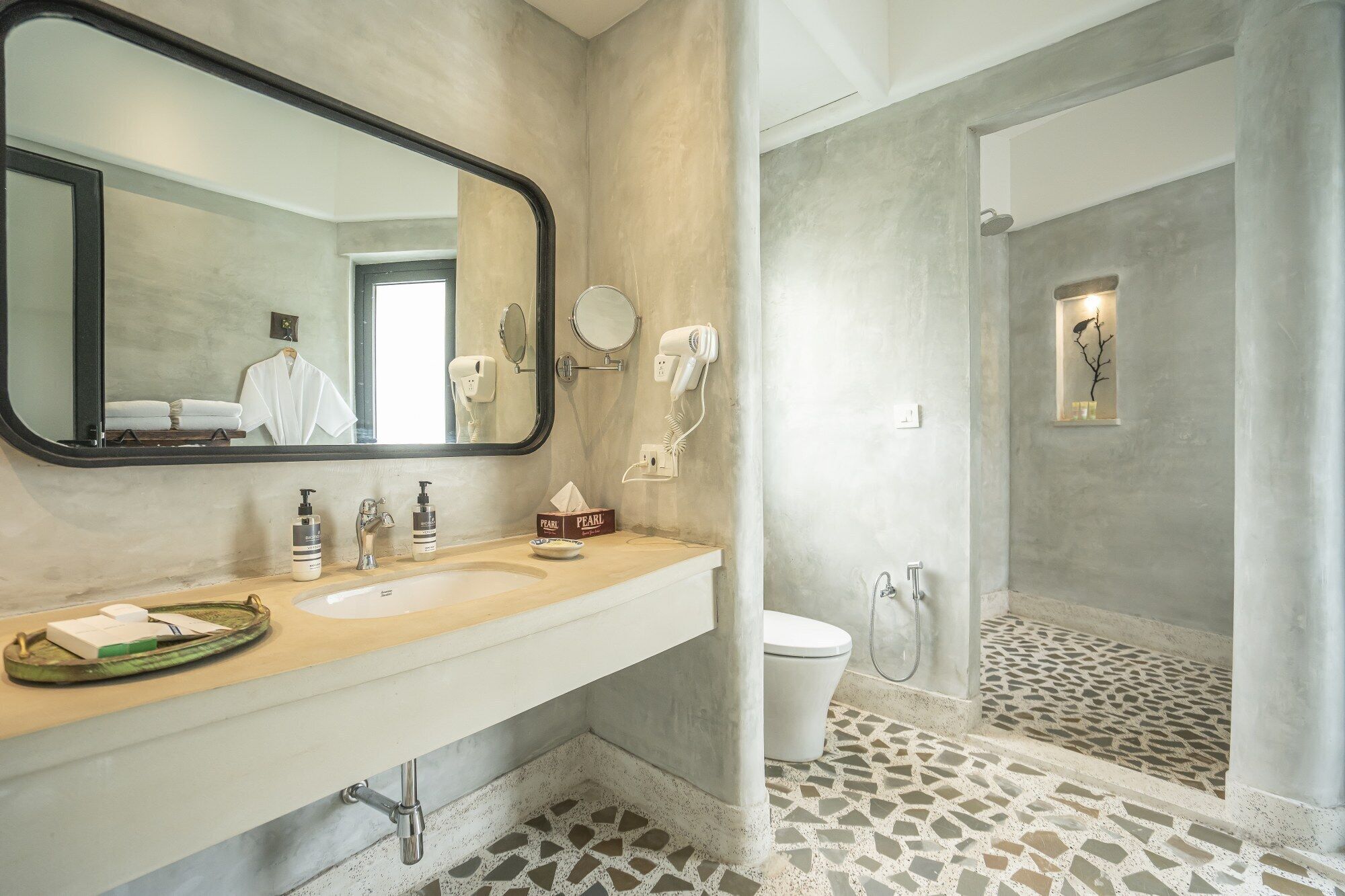 Une salle de bain avec un grand miroir, deux lavabos, des toilettes et un espace douche.