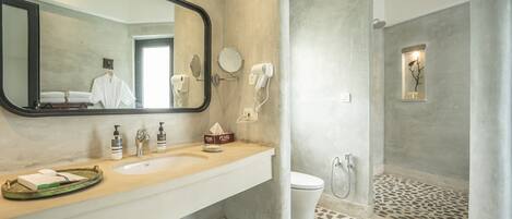 Une salle de bain avec un grand miroir, deux lavabos, des toilettes et un espace douche.