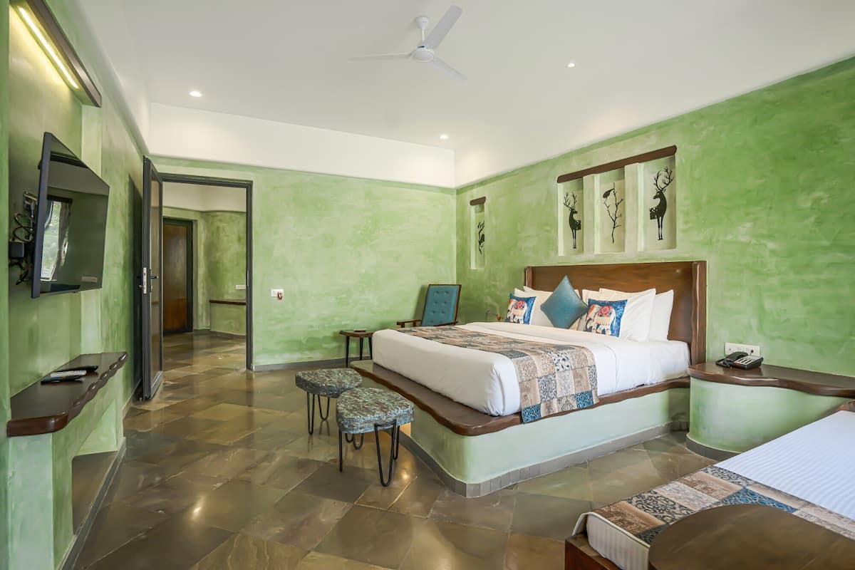 A hotel room with a large bed, a TV, a desk, and a chair.
