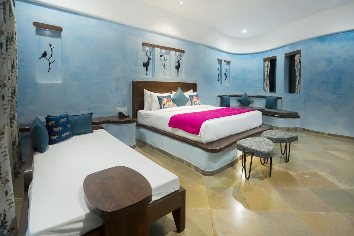 A modern bedroom with a large bed, a smaller bed, a bench, and a seating area.