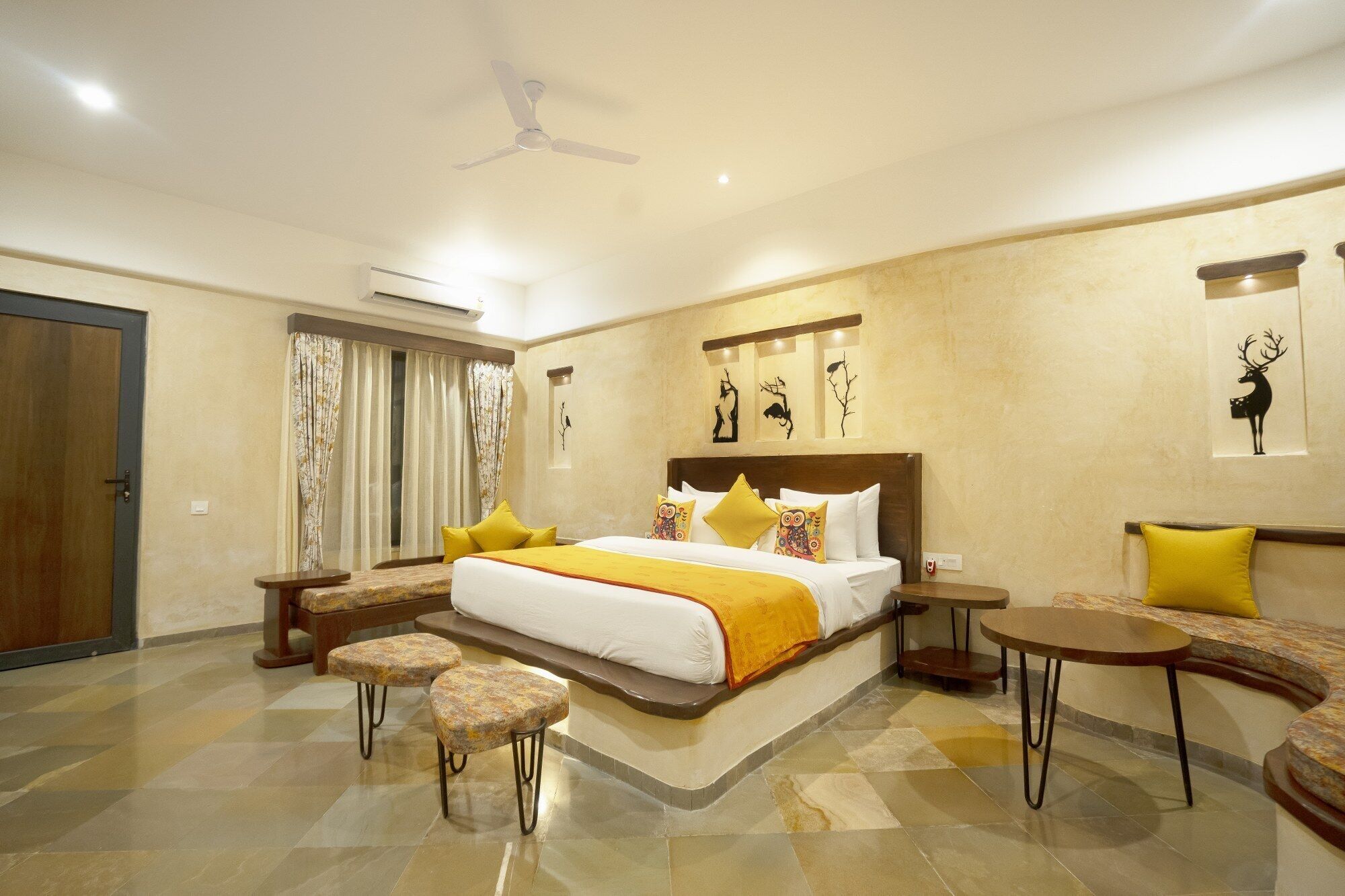 A spacious hotel room with a large bed, two side tables, a round coffee table, and a sofa.