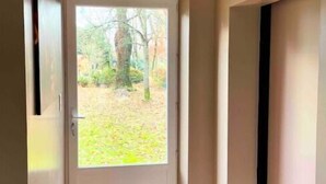Um corredor com uma porta branca que dá para um jardim.
