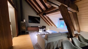 Ein Schlafzimmer im Dachgeschoss mit einem Schlafpodest, einer Couch und einem Fernseher.