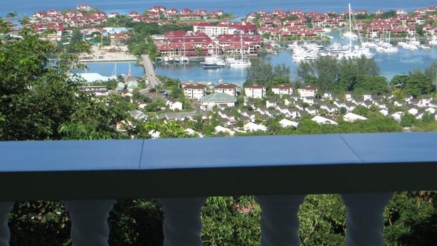 Una cittadina costiera con edifici a tetto rosso, un porto turistico con imbarcazioni e vista sul mare e isole sullo sfondo.