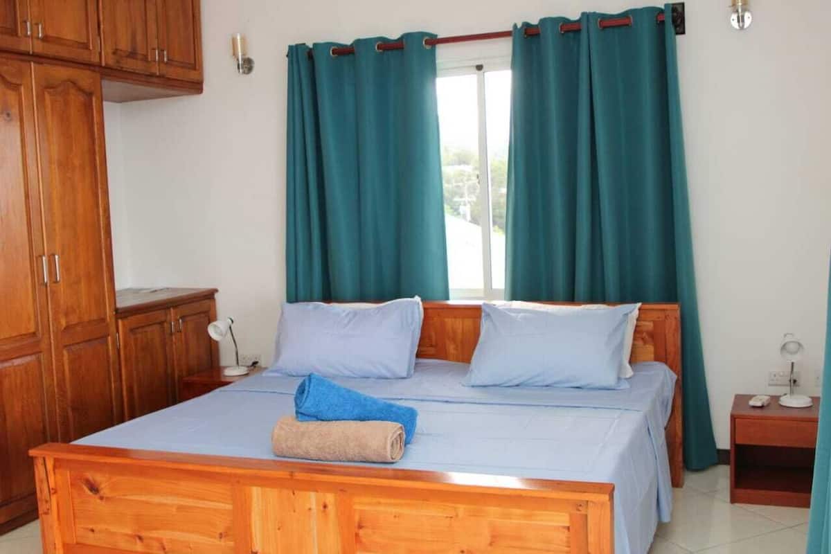 Un dormitorio con cama de madera, cortinas color turquesa y una ventana.