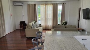 Un'ampia zona giorno con isola cucina, sgabelli da bar e divano.