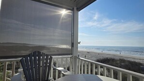 A covered deck with a view of the beach, a chair, and a table. - OCEAN FRONT @ CHERRY GROVE POINT - SALT AIR, SEA BREEZES, GORGEOUS SUNRISES (North Myrtle Beach)