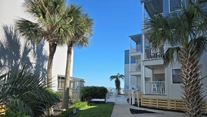 A residential building with balconies, palm trees, and a clear sky. - OCEAN FRONT @ CHERRY GROVE POINT - SALT AIR, SEA BREEZES, GORGEOUS SUNRISES (North Myrtle Beach)