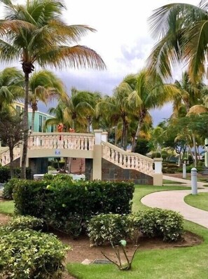 Guests may cross the picturesque bridge surrounded by lush greenery to access the resort's main building.