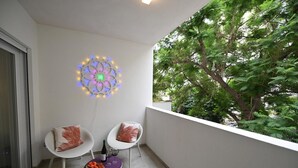 A balcony with two white chairs, a small table with a bottle and glasses, and a decorative light fixture. - Me too - Exclusive Apartments Studio Open Space Room 1 (BARI)