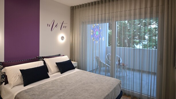 A bedroom with a bed, a wall-mounted light, and a view of an outdoor area with a table and chairs. - Me too - Exclusive Apartments Studio Open Space Room 1 (BARI)