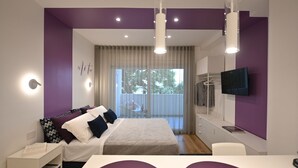 A modern bedroom with a bed, bedside table, and a TV mounted on the wall. - Me too - Exclusive Apartments Studio Open Space Room 1 (BARI)