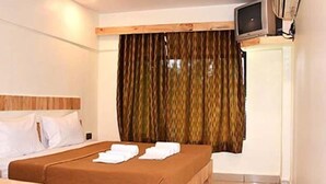 Una habitación de hotel con una cama, un televisor montado en la pared y una cortina.