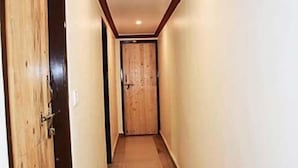 Un pasillo estrecho con puertas de madera a ambos lados y una pared lisa.