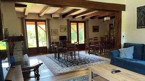A spacious living room with a wooden coffee table, blue sofa, and a dining area with wooden chairs and a table. - Les Costes, Calvignac. Large house with pool. Close to the river. (Calvignac)