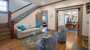 Un salon spacieux avec un escalier, un canapé, deux fauteuils et une table basse.