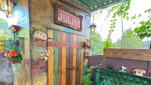 A rustic outdoor seating area with a green sofa and a wooden door labeled "JULIET." - HOSTAL VELVET  (Santa Ana)