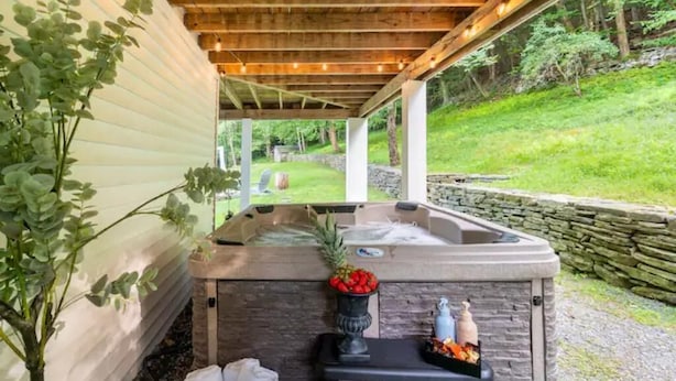 Ein Whirlpoolbereich mit einer Steinwand, einem kleinen Tisch mit Blumenvase und einer Holzpergola.