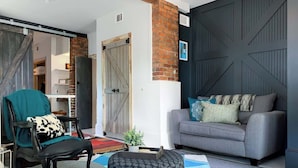 A living room with a sofa, a chair, a coffee table, and a patterned rug. - Stylish Savannah Condo Steps to Forsyth Park (Savannah)