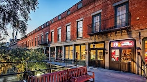 A brick building with a storefront and a bench in front. - Stylish Savannah Condo Steps to Forsyth Park (Savannah)