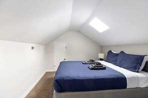 Une chambre à coucher avec un lit, une porte et une lucarne.