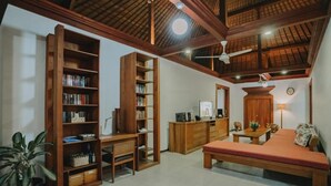 Un soggiorno accogliente con una libreria in legno, una scrivania, un divano e una ventola a soffitto.